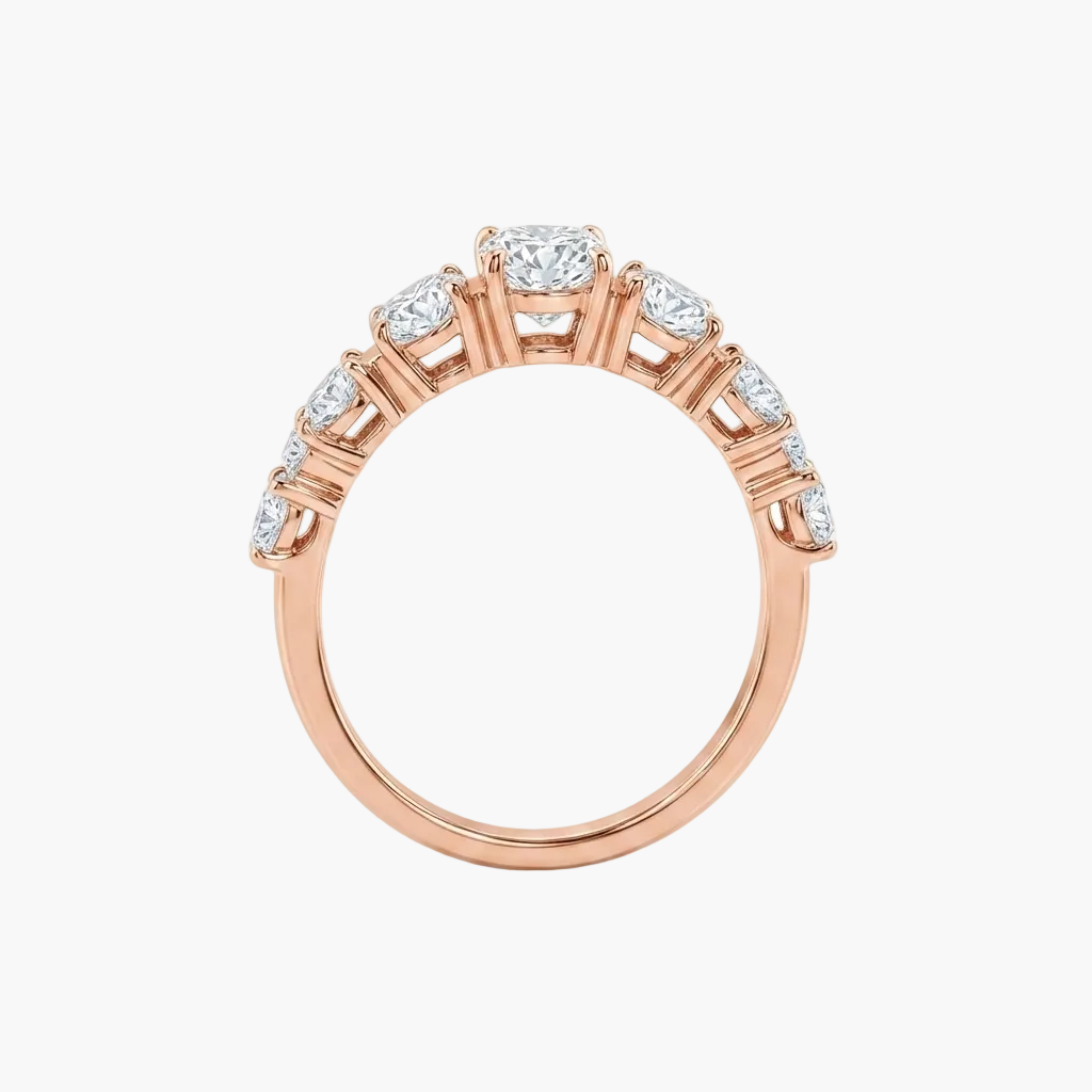 A rose gold diamond ring with a round-cut center stone and smaller diamonds set along the shoulders, shown on a clean white background.