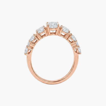 A rose gold diamond ring with a round-cut center stone and smaller diamonds set along the shoulders, shown on a clean white background.