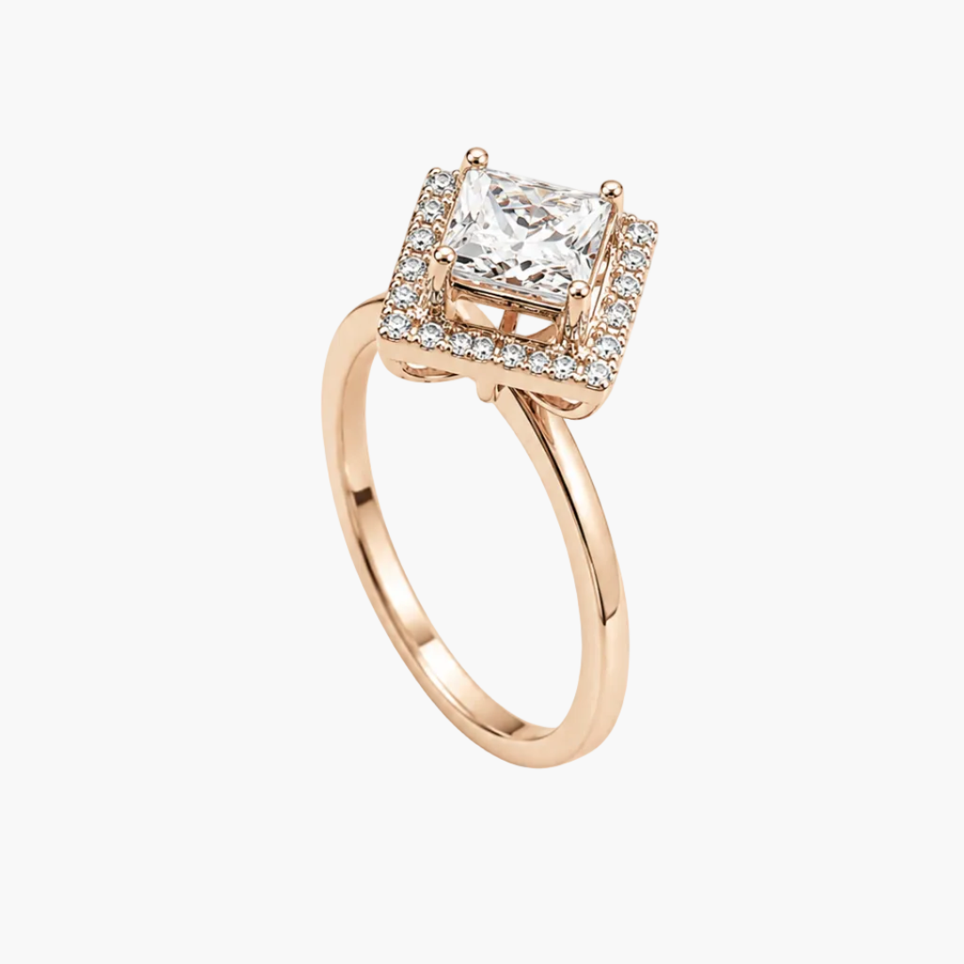 A rose gold engagement ring featuring a princess-cut diamond center stone surrounded by a halo of small diamonds, set on a polished band against a clean white background.