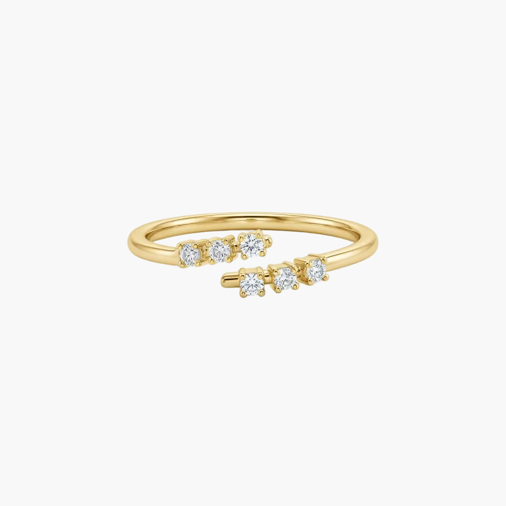 A delicate yellow gold ring with five small round-cut clear gemstones set along the band, photographed on a clean white background.