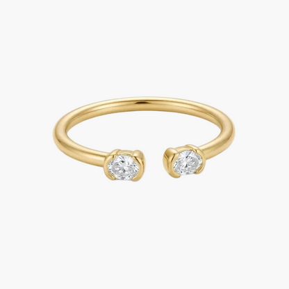 A slim yellow gold open cuff ring featuring two round-cut clear gemstones in prong settings, shown on a clean white background.
