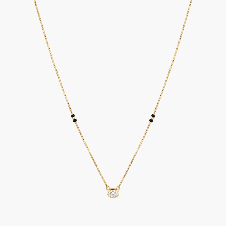 A delicate gold chain necklace featuring a small round clear gemstone pendant at the center and pairs of tiny black beads spaced along the chain, shown against a plain white background.