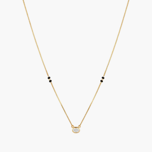 A delicate gold chain necklace featuring a small round clear gemstone pendant at the center and pairs of tiny black beads spaced along the chain, shown against a plain white background.