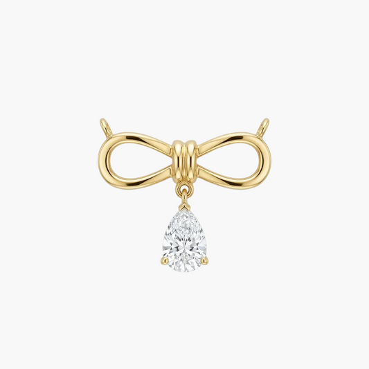 A gold bow-shaped stud earring with a dangling pear-cut clear gemstone, shown on a plain light gray background.