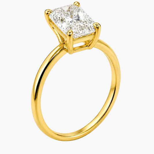 A yellow gold ring featuring a large, brilliant-cut diamond solitaire in a four-prong setting, shown on a clean white background.