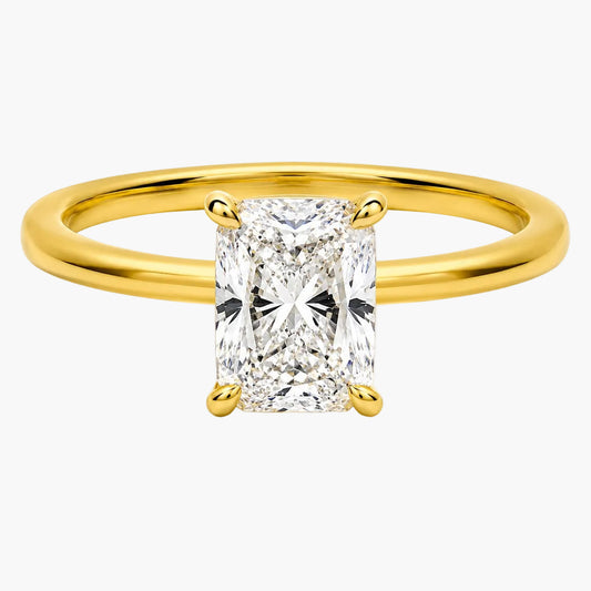 A yellow gold solitaire ring featuring a large rectangular radiant-cut diamond center stone in a four-prong setting, shown on a clean white background.