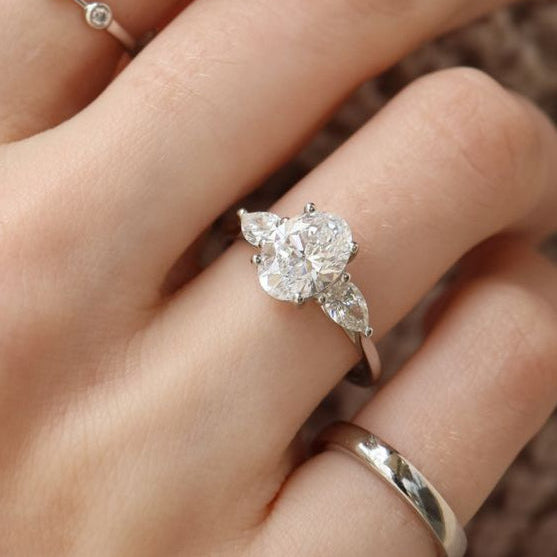 Close-up of a hand wearing two diamond rings with a blurred background