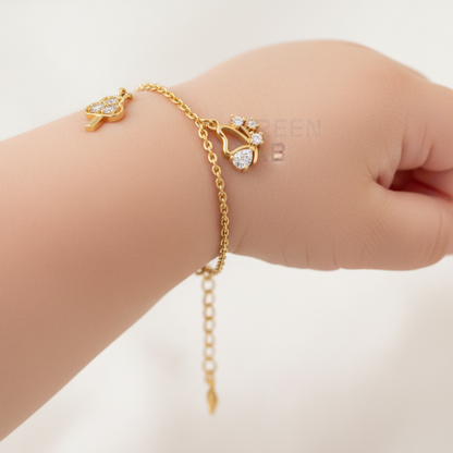Baby wearing delicate yellow gold diamond charm bracelet with arrow-cloud, butterfly and star diamond charms