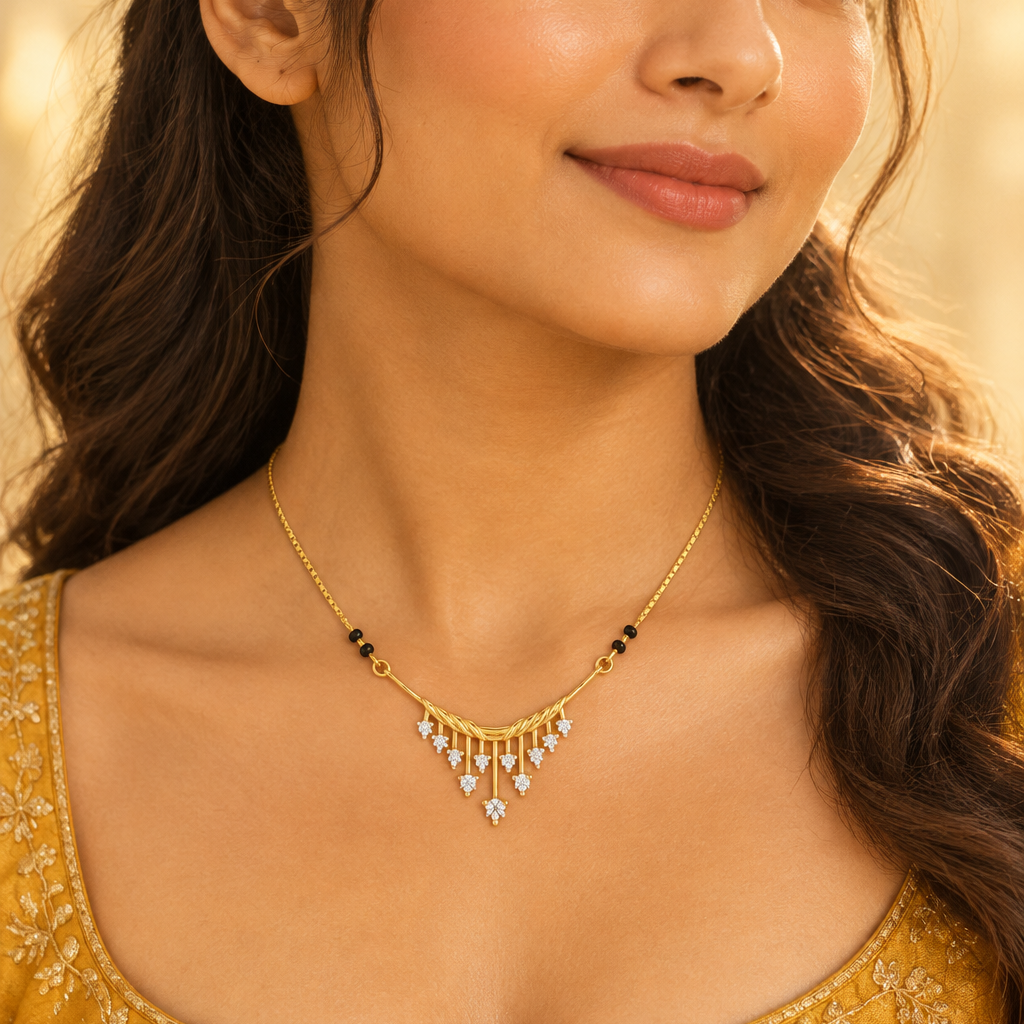 Beautiful elegant Indian female model with warm medium golden skin and hair in a soft romantic half-up style with loose waves wearing a very small delicate modern diamond mangalsutra featuring a fine yellow gold box chain with small traditional black beads meeting a chic Art Deco-inspired pendant — a wide gently curved horizontal bar with a beautiful twisted rope texture across its full length from which multiple slim straight vertical yellow gold rails hang downward graduating in height from shorter on the