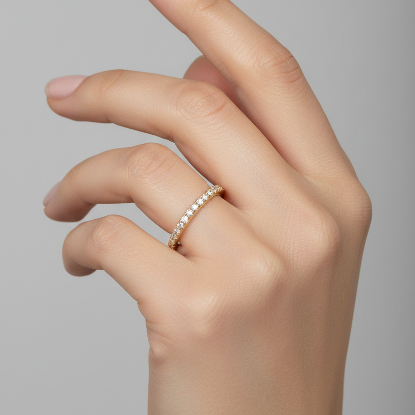 Female model wearing delicate slim yellow gold pavé diamond eternity wedding band ring