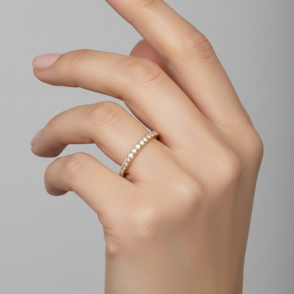 Female model wearing delicate slim yellow gold pavé diamond eternity wedding band ring