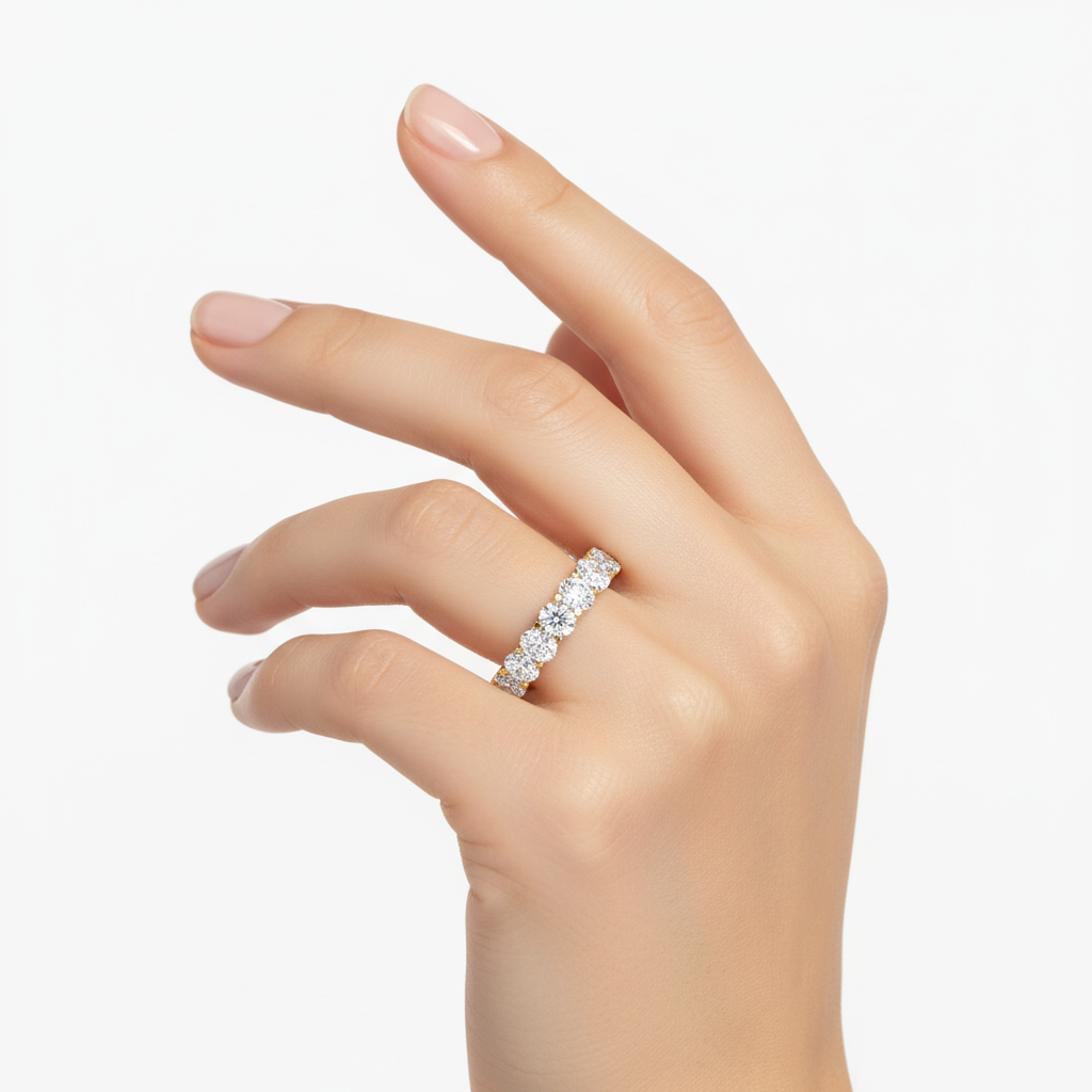 Female model wearing delicate yellow gold oval diamond eternity band