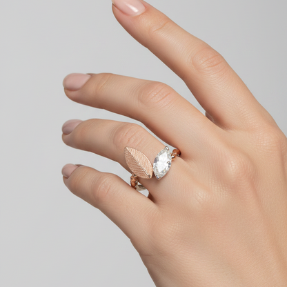 Female model wearing rose gold nature-inspired toi-et-moi bypass ring with matte engraved leaf motif and large east-west marquise diamond in white gold V-prong setting on beaded shoulder band