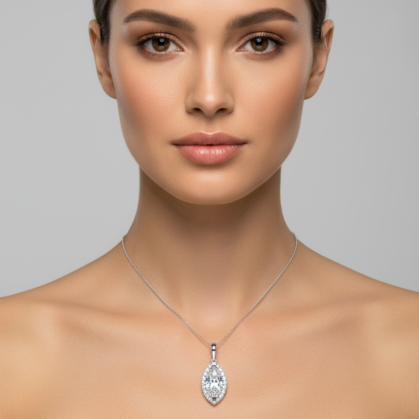 Female model wearing small white gold marquise-cut diamond halo pendant necklace with vertical marquise center stone surrounded by continuous round brilliant diamond halo border on fine white gold chain