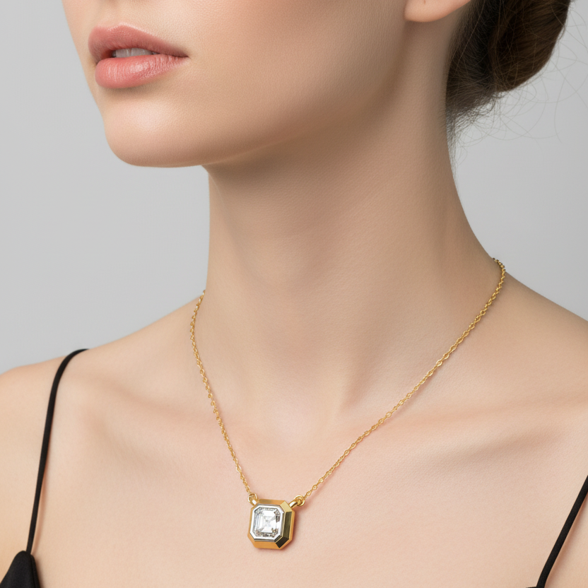 Female model wearing small yellow gold Asscher-cut diamond solitaire pendant with bold geometric chamfered bezel