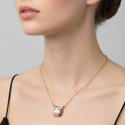 Female model wearing small yellow gold Asscher-cut diamond solitaire pendant with bold geometric chamfered bezel