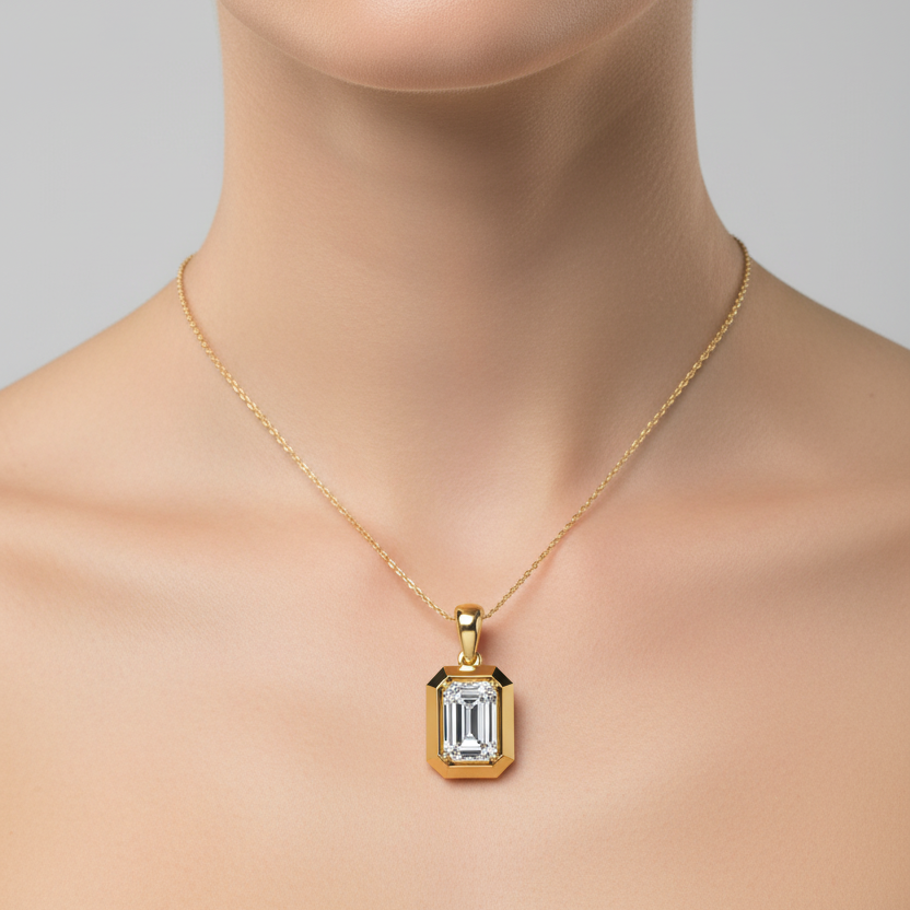 Female model wearing small yellow gold emerald-cut diamond solitaire pendant in octagonal frame