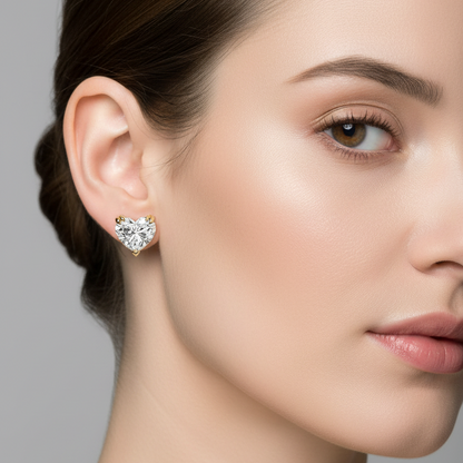 Female model wearing small yellow gold heart-cut diamond solitaire stud earrings
