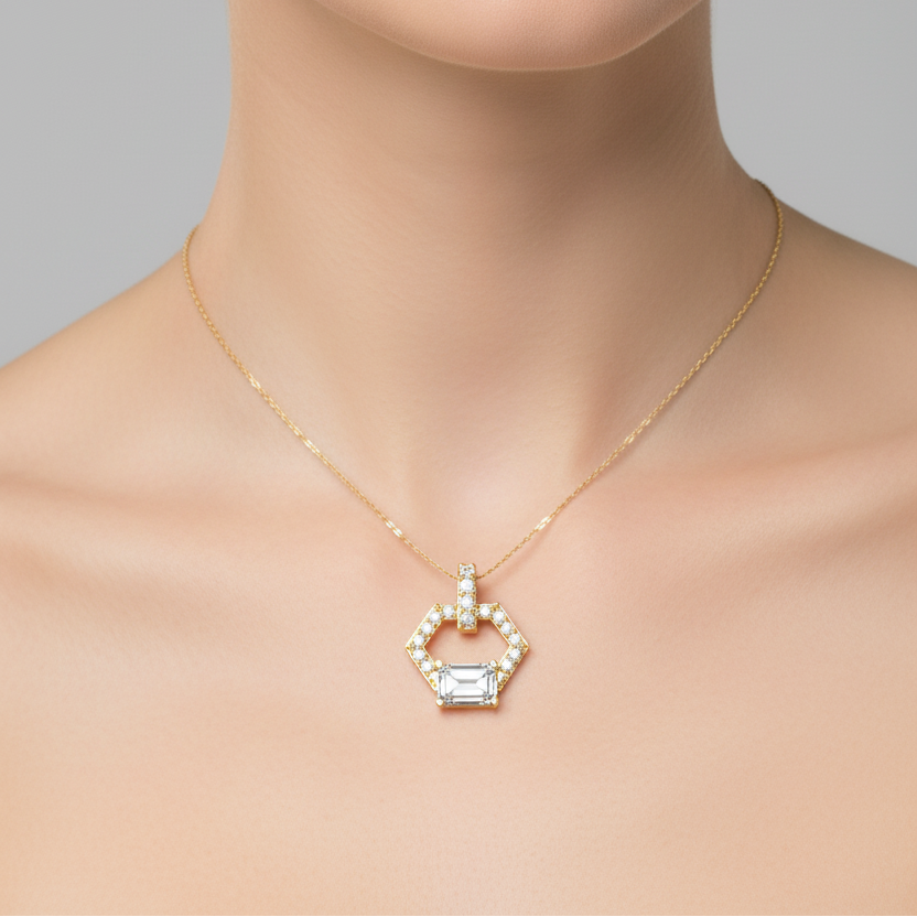 Female model wearing small yellow gold hexagonal open frame emerald-cut diamond pendant necklace