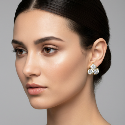 Female model wearing small yellow gold mixed-cut three-stone cluster diamond stud earrings with princess and round diamonds