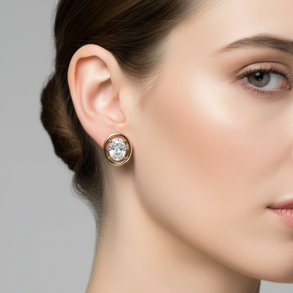 Female model wearing small yellow gold oval diamond solitaire stud earrings with double concentric oval frame
