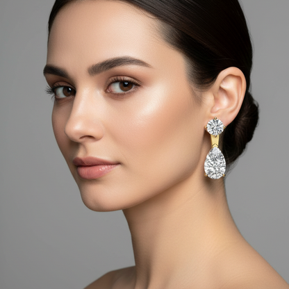 Female model wearing small yellow gold round and pear diamond two-stone drop earrings