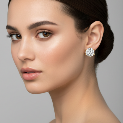 Female model wearing small yellow gold six-prong round brilliant diamond solitaire stud earrings