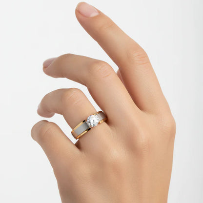 Hand wearing a two-tone ring with a diamond on a light gray background