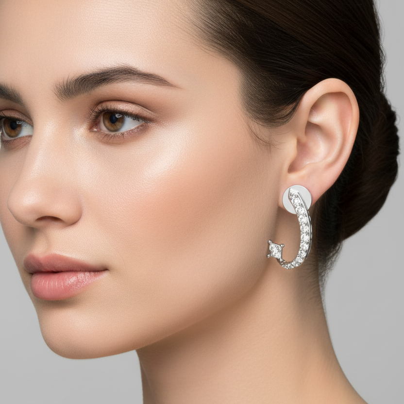 Female model wearing very small white gold J-shaped ear crawler jacket earrings with a flat circular disc stud anchor at the top with a small chevron arrow tip set with a tiny round brilliant diamond pointing upward and a slim curved J-bar set with graduating round brilliant diamonds from small to large wrapping under the earlobe terminating in a small princess-cut diamond in four ball-tipped corner prongs at the bottom tip