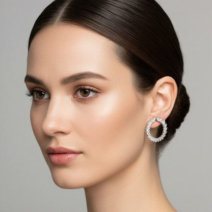 Female model wearing very small white gold open circle hoop earrings with alternating tangentially-set marquise-cut and round brilliant diamonds in a continuous flowing laurel wreath feather pattern along the front arc sitting close and delicate near the earlobe