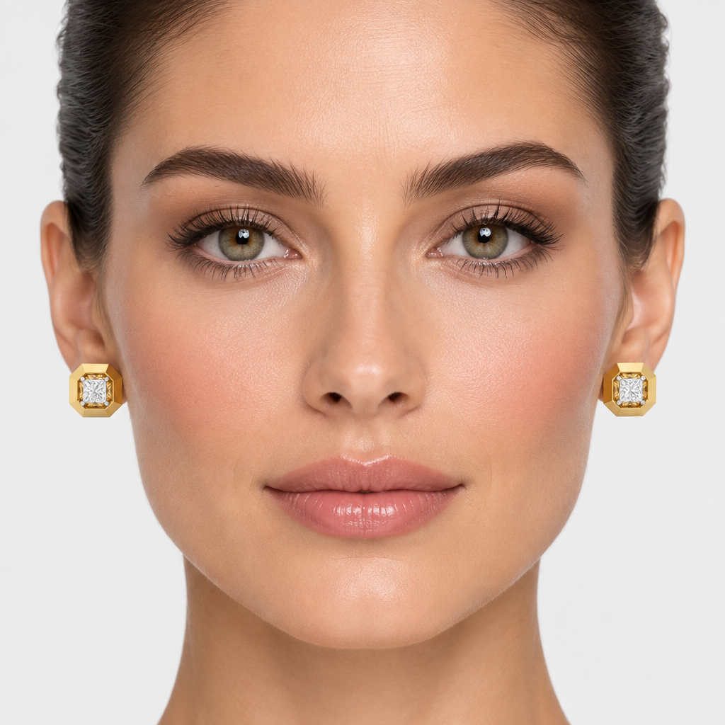 Female model wearing very small yellow gold architectural octagonal princess-cut diamond stud earrings with a wide thick high-mirror polished regular octagon outer frame featuring chamfered angled edges between each flat polished face with a deep square recessed channel cavity cut into the center interior walls angled and faceted creating a brilliant reflective inner surround around a large princess-cut diamond in four white gold ball-tipped corner prong settings sitting flat and compact against the earlobe
