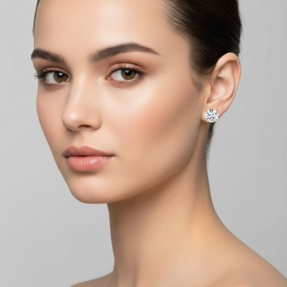 Female model wearing very small yellow gold round brilliant diamond solitaire stud earrings in a distinctive eight-prong double-claw setting with pairs of small rounded ball-tipped yellow gold prongs at north south east and west positions gripping each large sparkling round brilliant diamond flush against the earlobe