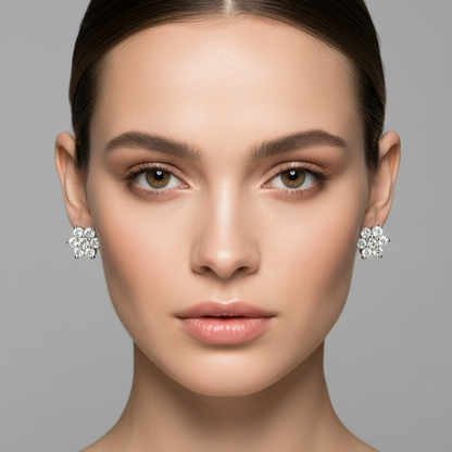 Female model wearing very small yellow gold seven-stone diamond flower cluster stud earrings with one large round brilliant diamond at the center surrounded by six equal round brilliant diamonds in a complete tight circle all held in white gold shared ball-tipped prong settings forming a seamless daisy flower cluster sitting perfectly flat and compact against the earlobes sparkling brilliantly as one unified blaze of light with the yellow gold backing only visible from the rear hair pulled back in a sleek u