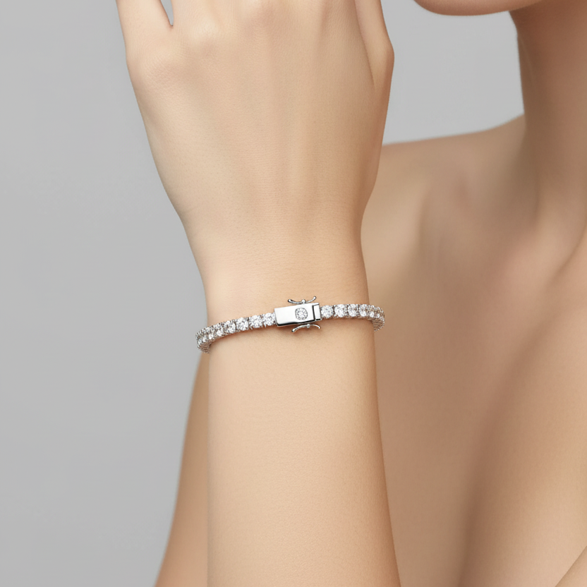 Female model wearing white gold classic diamond tennis bracelet with four-prong settings and push-button diamond-topped box clasp