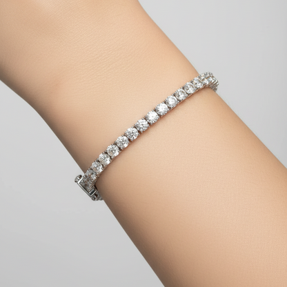 Female model wearing white gold classic large diamond tennis bracelet with four-prong settings and ornate articulated back