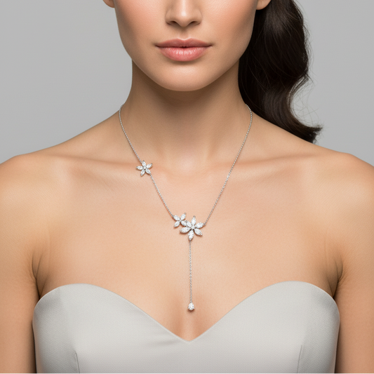 Female model wearing white gold diamond flower lariat Y-necklace with asymmetric marquise-petal flower clusters on delicate rope chain and long lariat drop ending in pear diamond pendant