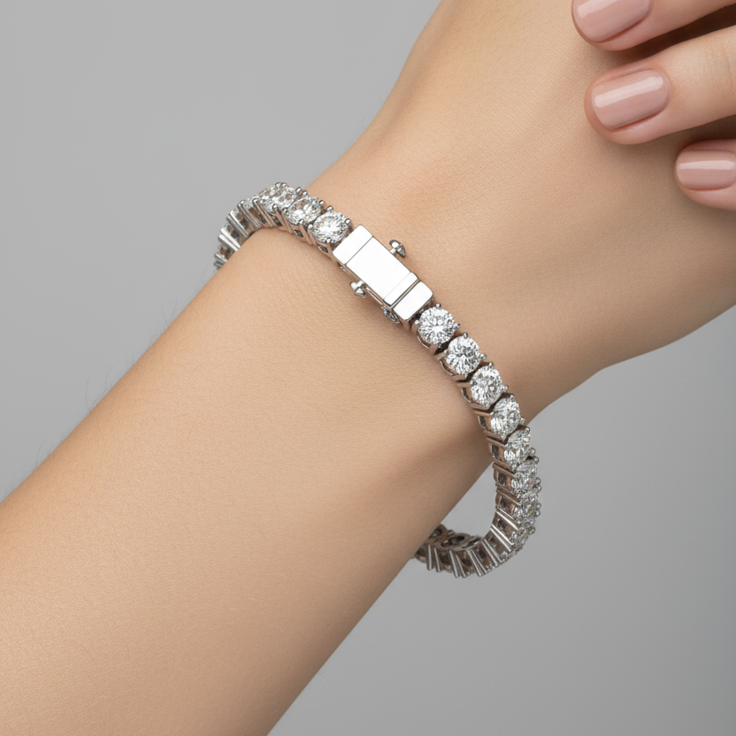 Female model wearing white gold large diamond tennis bracelet with four-prong settings and push-button box clasp
