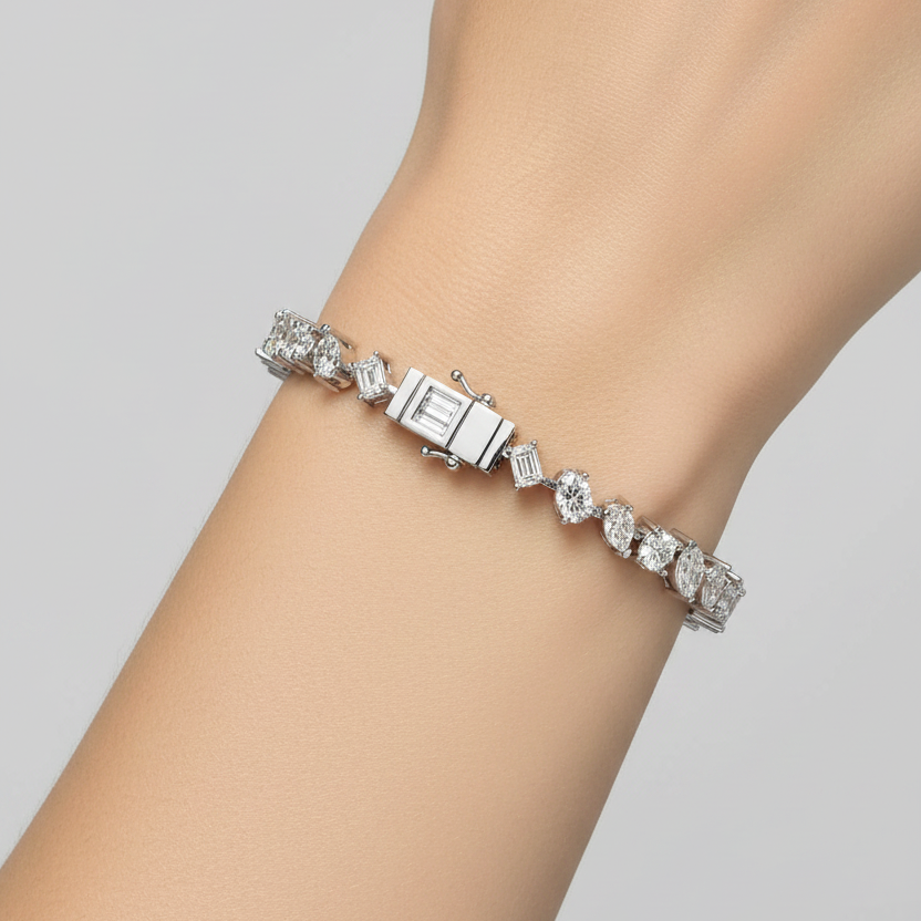 Female model wearing white gold mixed-cut diamond tennis bracelet with alternating round, baguette, pear and marquise diamonds
