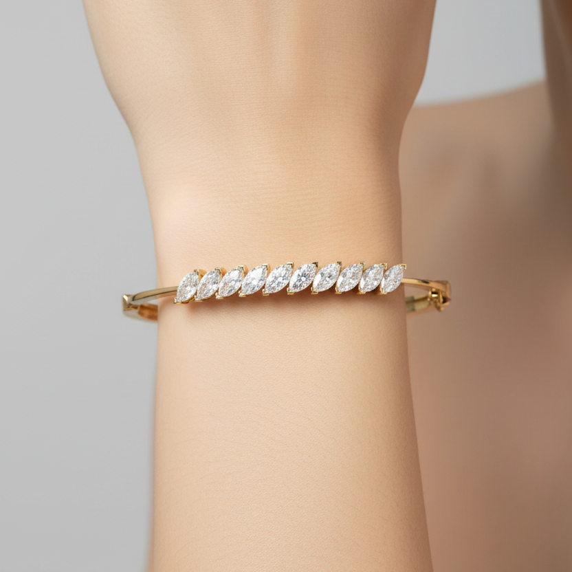 Female model wearing yellow gold bangle bracelet with diagonal marquise diamond cluster