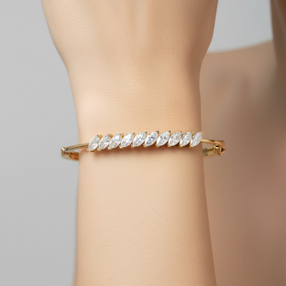 Female model wearing yellow gold bangle bracelet with diagonal marquise diamond cluster