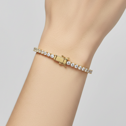 Female model wearing yellow gold classic diamond tennis bracelet with four-prong settings
