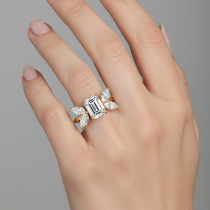 Female model wearing yellow gold emerald-cut diamond cluster ring with marquise and oval side stones in botanical silhouette