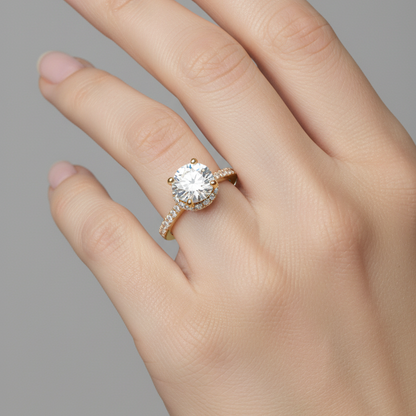 Female model wearing yellow gold round brilliant diamond hidden halo engagement ring with pavé band