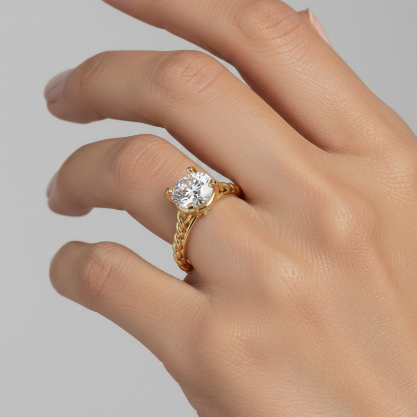 Female model wearing yellow gold round brilliant diamond solitaire engagement ring with four square flat-tipped claw prongs, hidden burnish-set shoulder diamond accents and bold twisted rope texture band