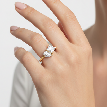 Female model wearing yellow gold toi et moi two-stone ring with princess-cut and pear-cut diamonds