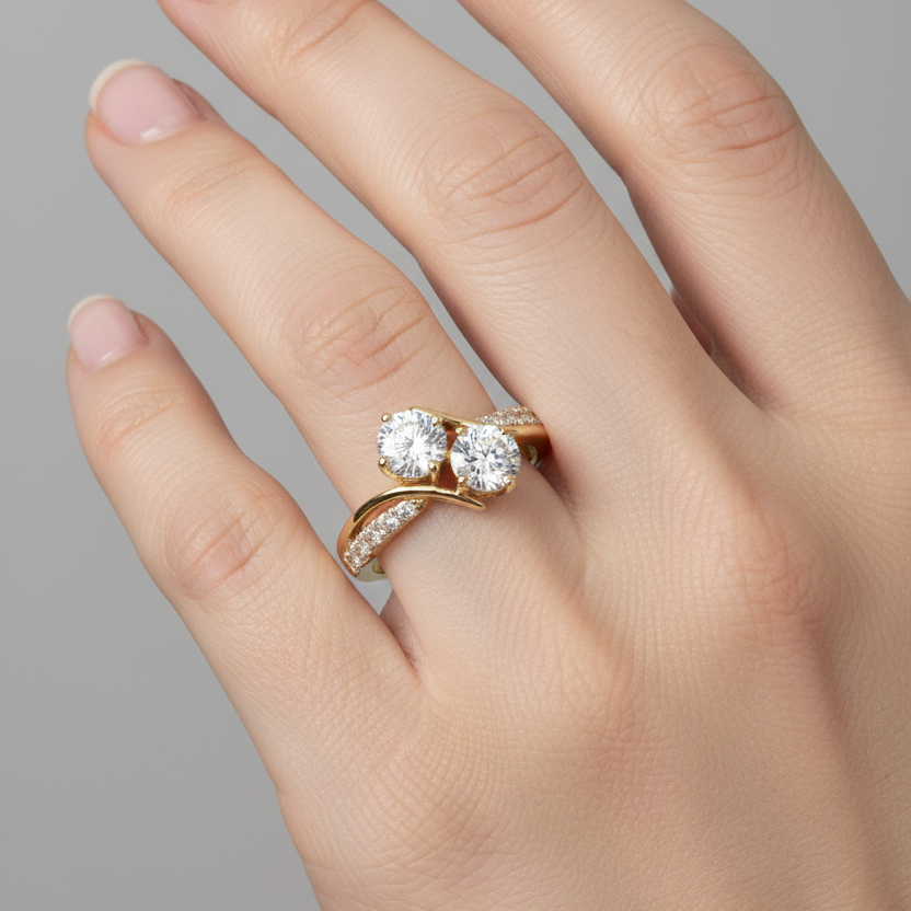 Female model wearing yellow gold two-stone toi-et-moi bypass ring with two large round brilliant diamonds in diagonal arrangement and split pavé diamond shoulder on one side