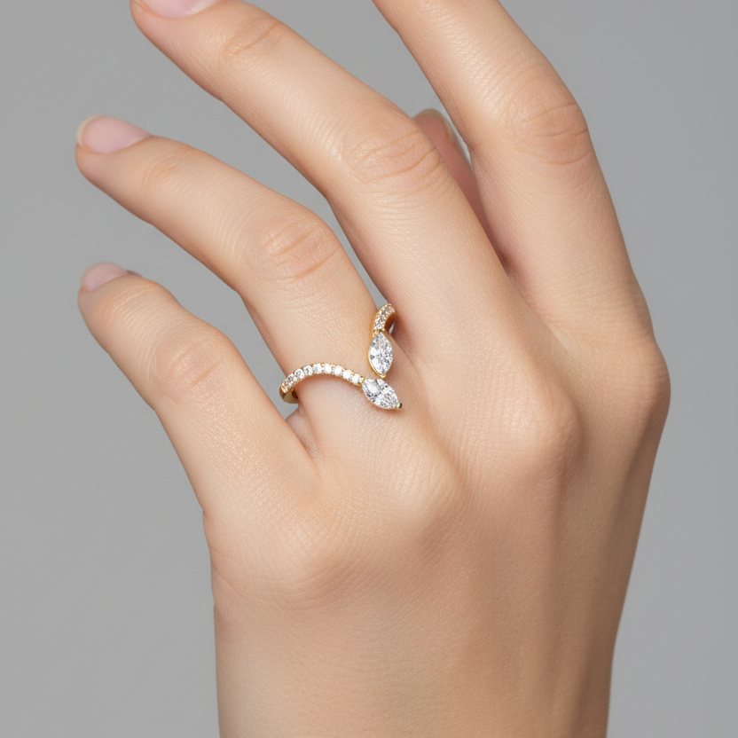 Female model's hand wearing a small delicate yellow gold two-stone V-shaped chevron bypass ring with graduating round brilliant micro-pavé diamonds along both outward-sweeping arms and two crossed marquise-cut diamonds in diagonal toi-et-moi butterfly wing arrangement at the central meeting point