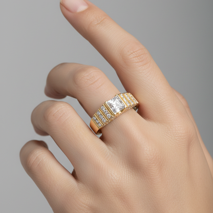 Female model's hand wearing a small yellow gold Art Deco-style princess-cut diamond ring with the center diamond set flush in a square yellow gold frame flanked on both sides by bold stepped architectural parallel raised yellow gold ridges with tiny round brilliant micro-pavé diamonds sparkling in the grooves between the ridges on a smooth tapered yellow gold band