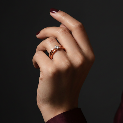 Hand wearing a gold ring with a diamond on a dark background