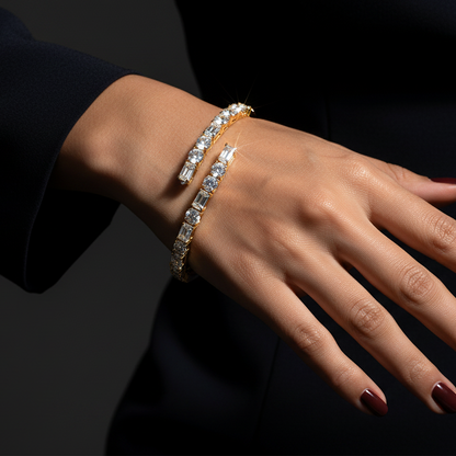 Generated dramatic cinematic studio editorial variation - beautiful Indian female model wearing the yellow gold alternating round brilliant and baguette diamond bypass bangle bracelet, strong directional side light against near-black background with overhead top-down angle showing all diamonds blazing with extraordinary icy prismatic fire and warm golden rim light on the bypass bangle, deep red nails and dark navy sleeve